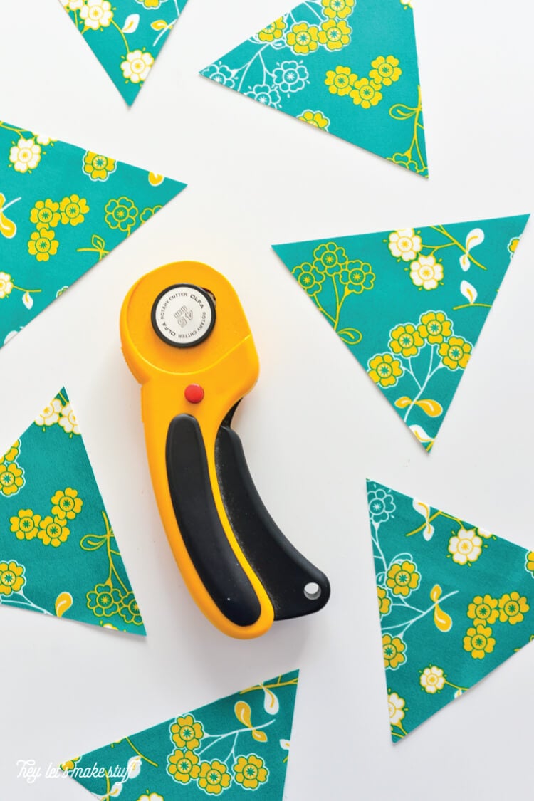 A fabric cutter and pieces of material cut into triangles all sitting on a table