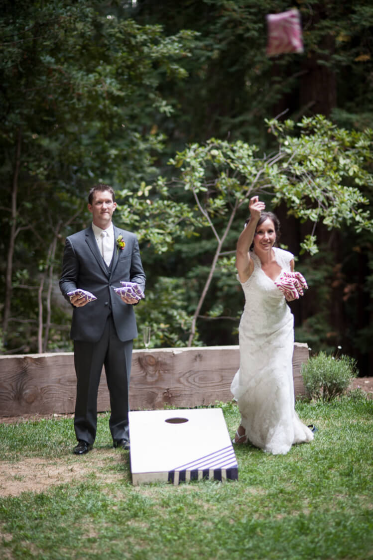 bride and groom playing cornhole game on wedding day