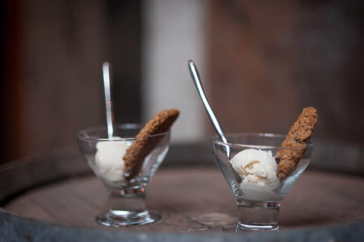 Two dessert cups filled with ice cream, a spoon and a cookie