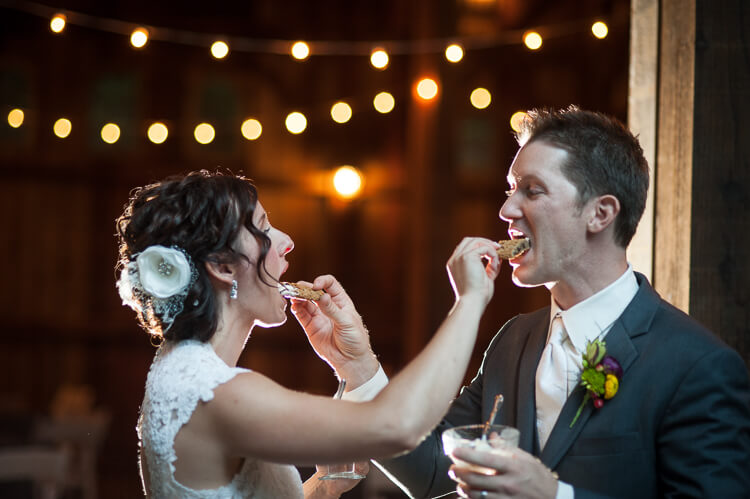 A bride and a groom feeding each other a cookie