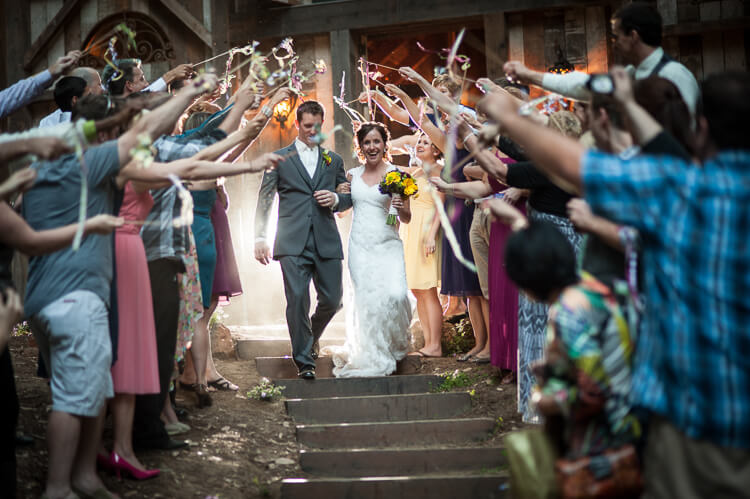 A group of people waving streamer as the bride and groom walk down the steps