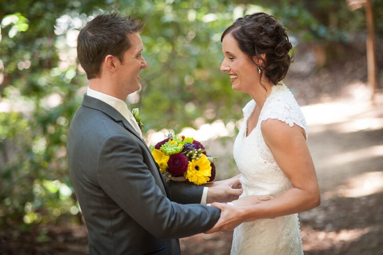 A bride and a groom standing among trees