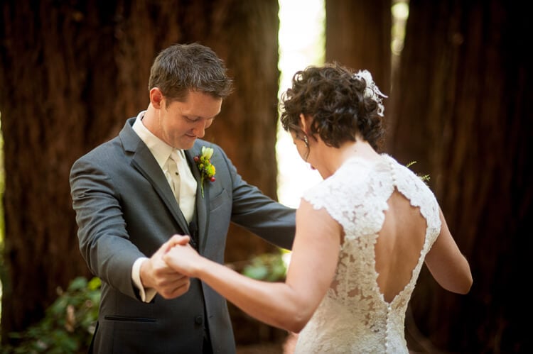 A bride and a groom standing among trees