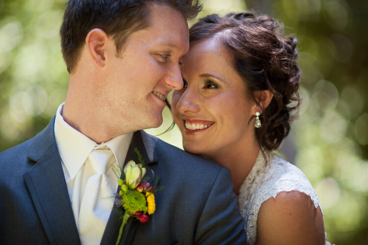 A close up of a bride and groom smiling at each other