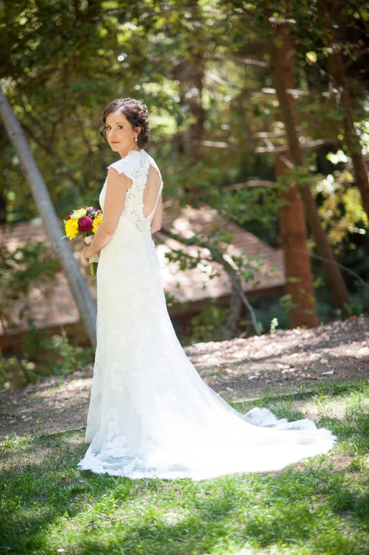 Full picture of a bride holding a bouquet of flowers and showing the back of her dress and train