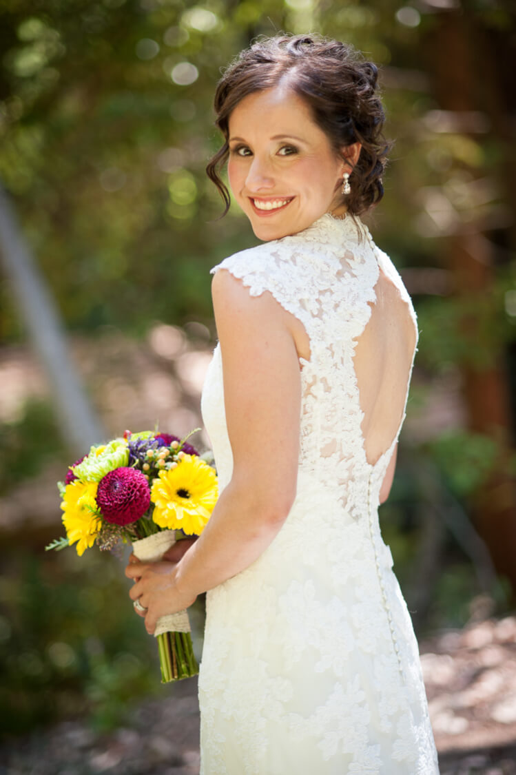 A bride holding a bouquet of flowers and posing with a smile for the camera