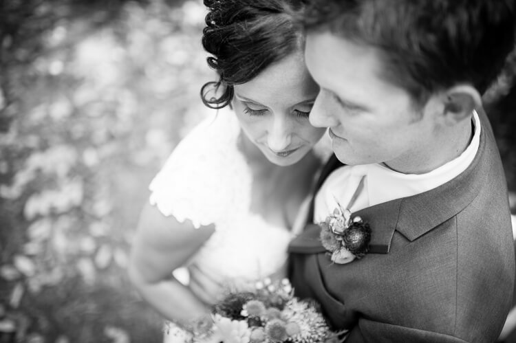 A black and white phots of a close up of a bride and a groom hugging each other