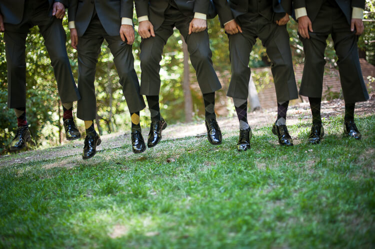 A group of men jumping up in the air and holding up their pants legs to show off their socks