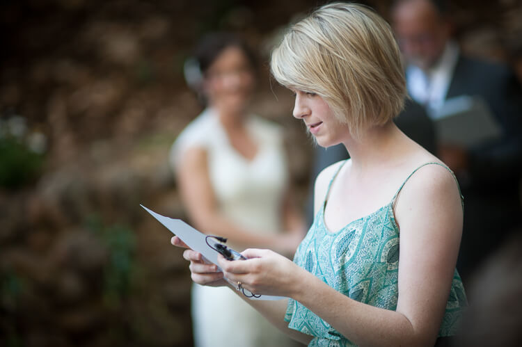 A woman in a blue dress reading from a piece of paper