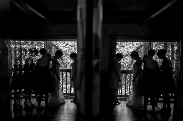 A mirror reflection of woman helping a bride into her dress