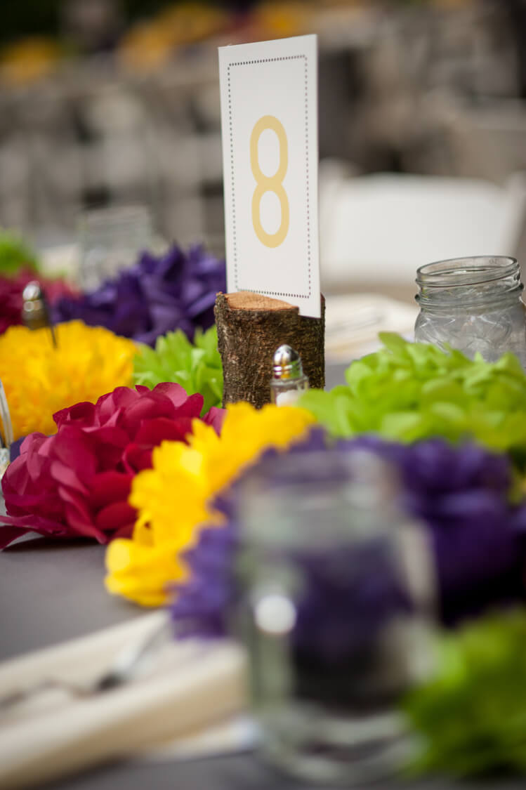 A close up of a paper cut flowers, a table number and place settings on a table