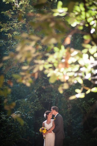 A bride and a groom standing in front of a tree