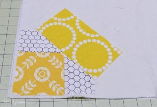 Pieces of fabric quilted and laid out on top of a piece of batting