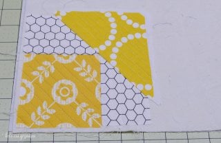 Pieces of fabric quilted and laid out on top of a piece of batting