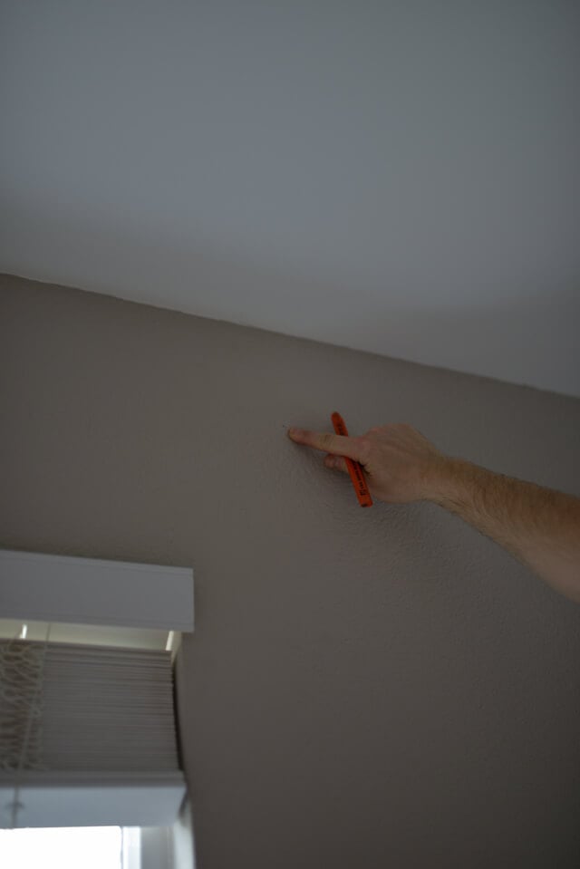 man marking spot with pencil where to hang curtains