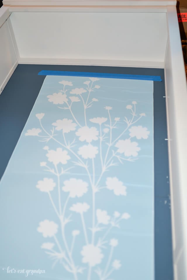 floral decal placed on bookshelf with blue tape