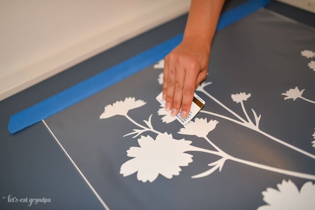 woman's hand using credit card to stick wall decal on bookshelf