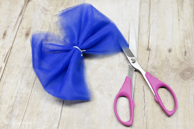 blue tulle tied in a bow and scissors cutting sides to separate layers