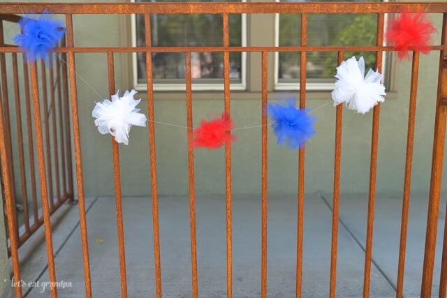 red, white, and blue tulle DIY firework poofs strung on fence