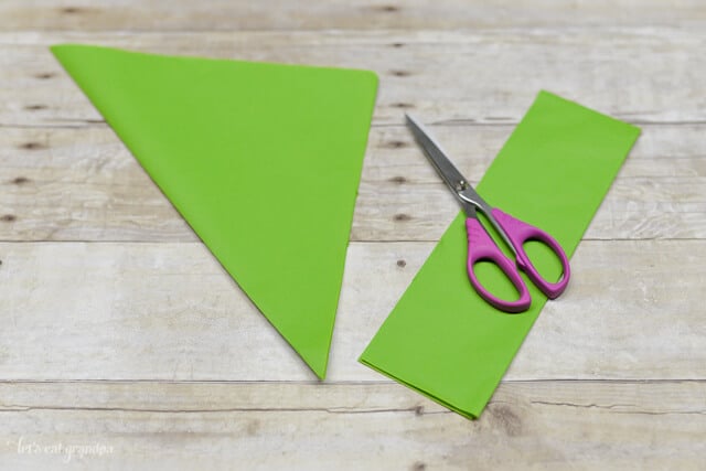 green tissue paper sheet on wooden background with folded corner side cut off