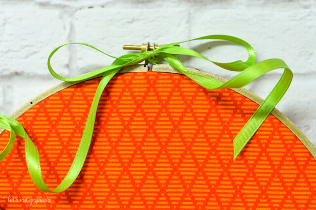 green ribbon tied to top of orange pumpkin embroidery hoop