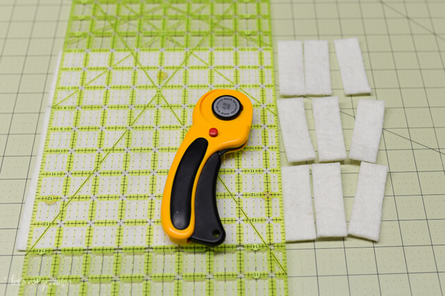 rotary cutter, cutting mat and strips of white felt cut 