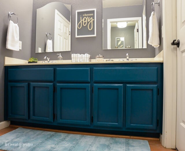 Choose joy floating artwork in bathroom above teal cabinets