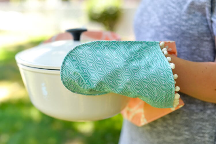 A woman holding a huge pan using a potholder