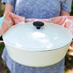 A woman holding a huge pan using a potholder