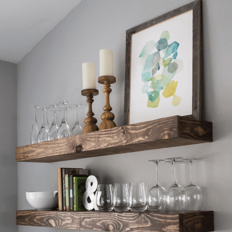 wooden floating shelves in kitchen with glasses and home decor