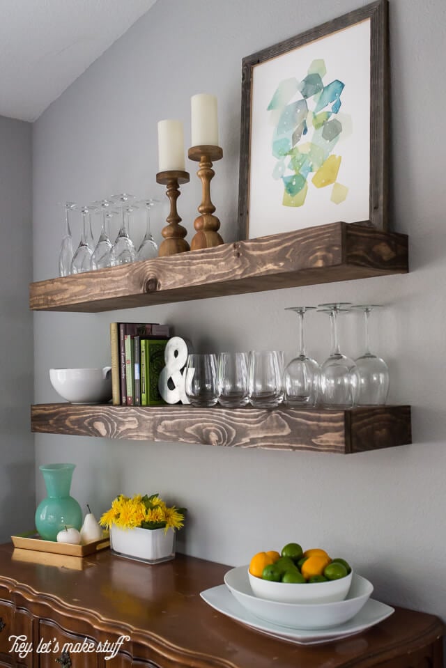 wooden floating shelves in kitchen with glasses and home decor