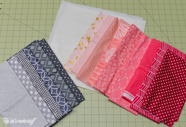 various fabric squares in red, gray, pink and black on sewing mat