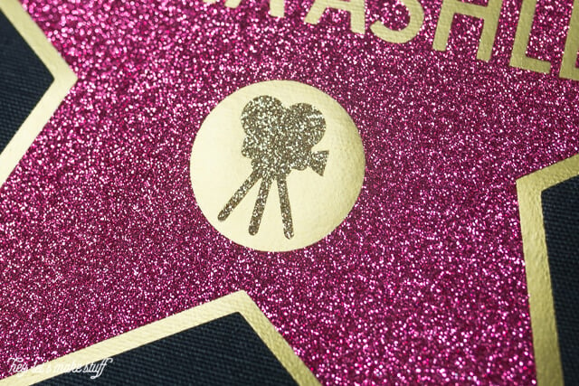 Close up image of a movie camera on top of a partial picture of a pink and gold star