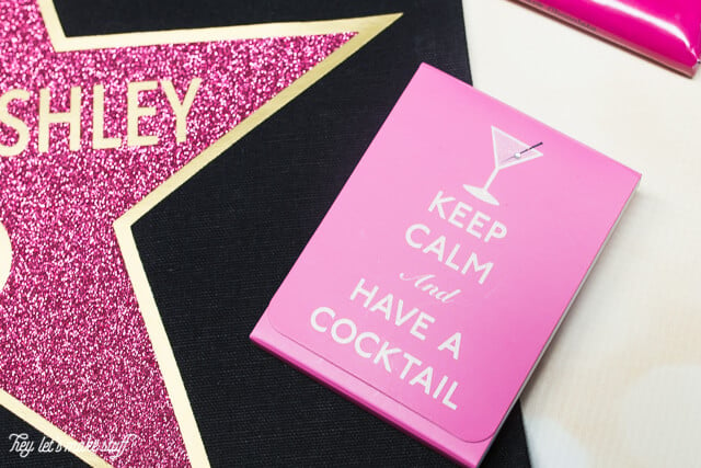 A close up of a pink notebook decorated with an image of a cocktail and the words, \"Keep Calm and Have a Cocktail\"