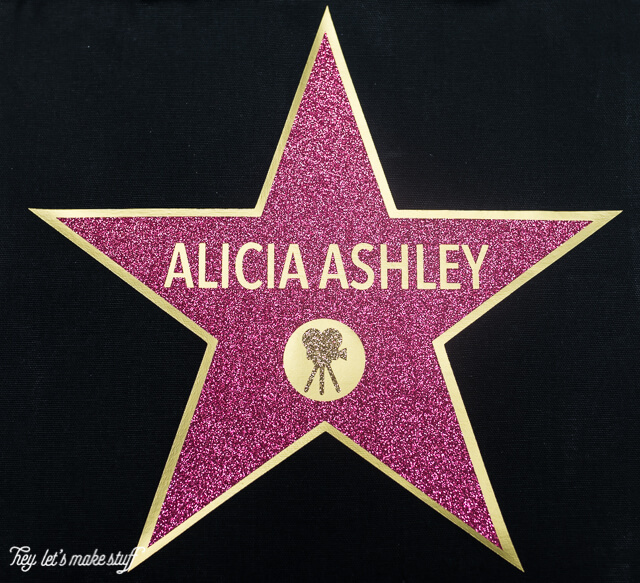 Image of a gold star with a pink personalized star over the top of it and an image of a movie camera applied to it, all against a black background 