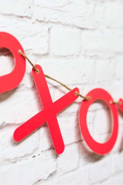A red "X" and "O" banner hanging on a white brick wall