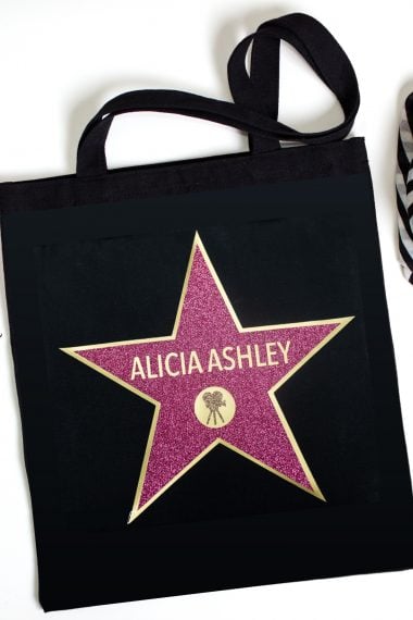 A black tote bag decorated with a star and personalized with a name