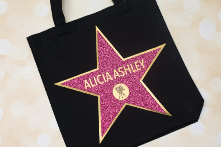 Close up of a back tote decorated with a pink and gold start and a personalized name