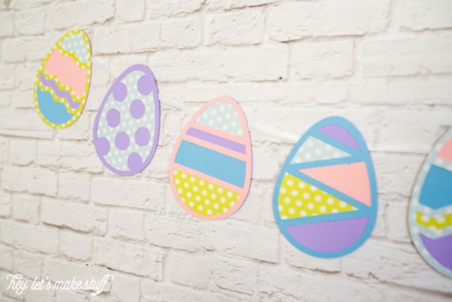 Easter Egg banner cut from paper hanging on a white brick wall