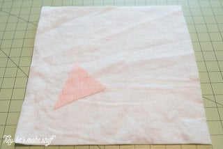 A piece of batting and a triangular piece of fabric sitting on top of a mat