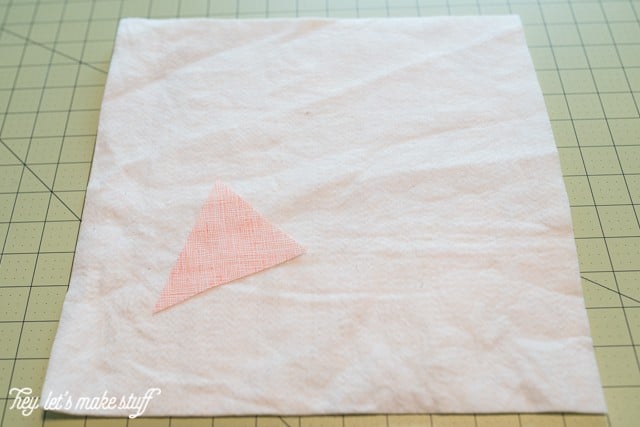 A piece of batting and a triangular piece of fabric sitting on top of a mat