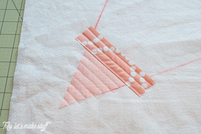 A close up of a triangular and a rectangular piece of fabric quilted to a piece of batting