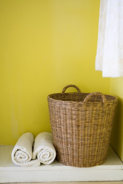 A close up of a basket sitting on a shelf with two rolled up white towels next to it