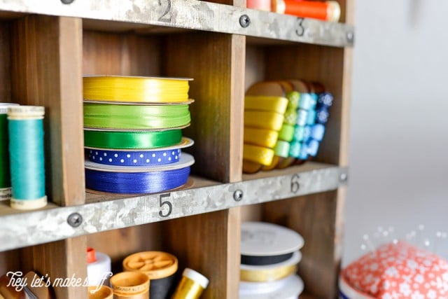 wooden cubby organizer displaying colorful ribbons and spools of thread