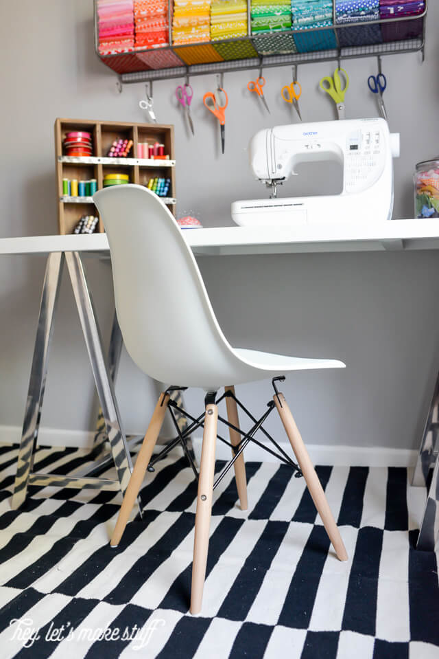 desk in craft room with black and white rug, white chair, and sewing machine on table