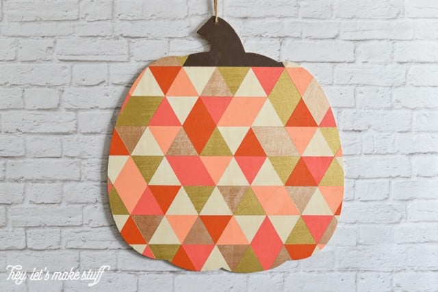 finished painted geometric pumpkin hung on white brick wall