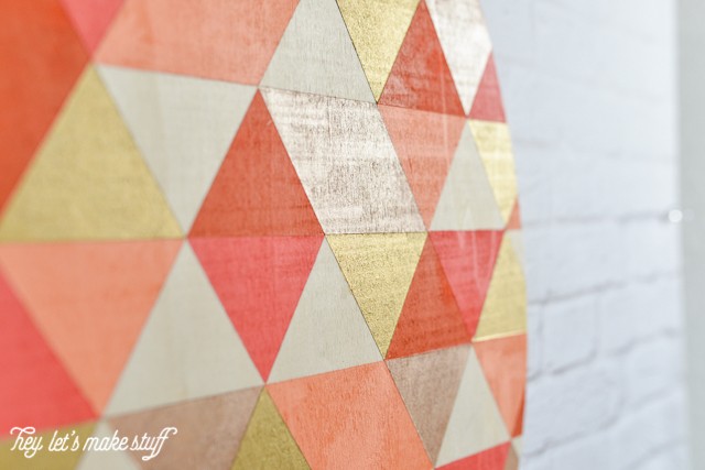 side view of finished geometric painted pumpkin hanging on white brick fireplace