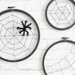 Turn some simple craft supplies—yarn and an embroidery hoop—into spooky Halloween spider hoops!