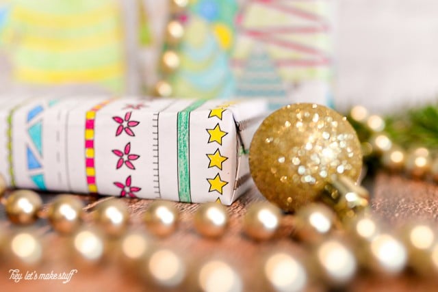 A gold Christmas ornament and beads lying on a table next to a wrapped present