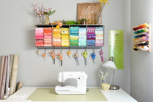 craft room with sewing machine on table and pretty colored fabrics and scissors organized above